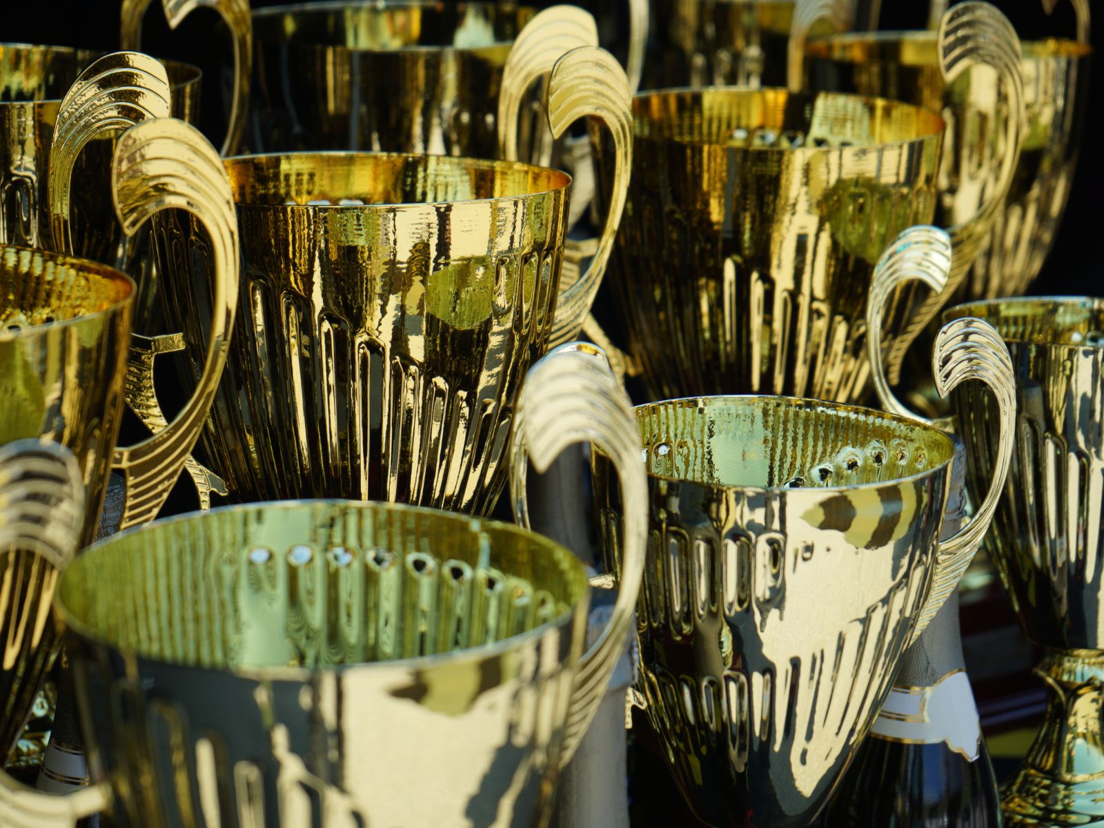Shiny gold trophies with ribbed design, perfect for sports awards and corporate recognition.