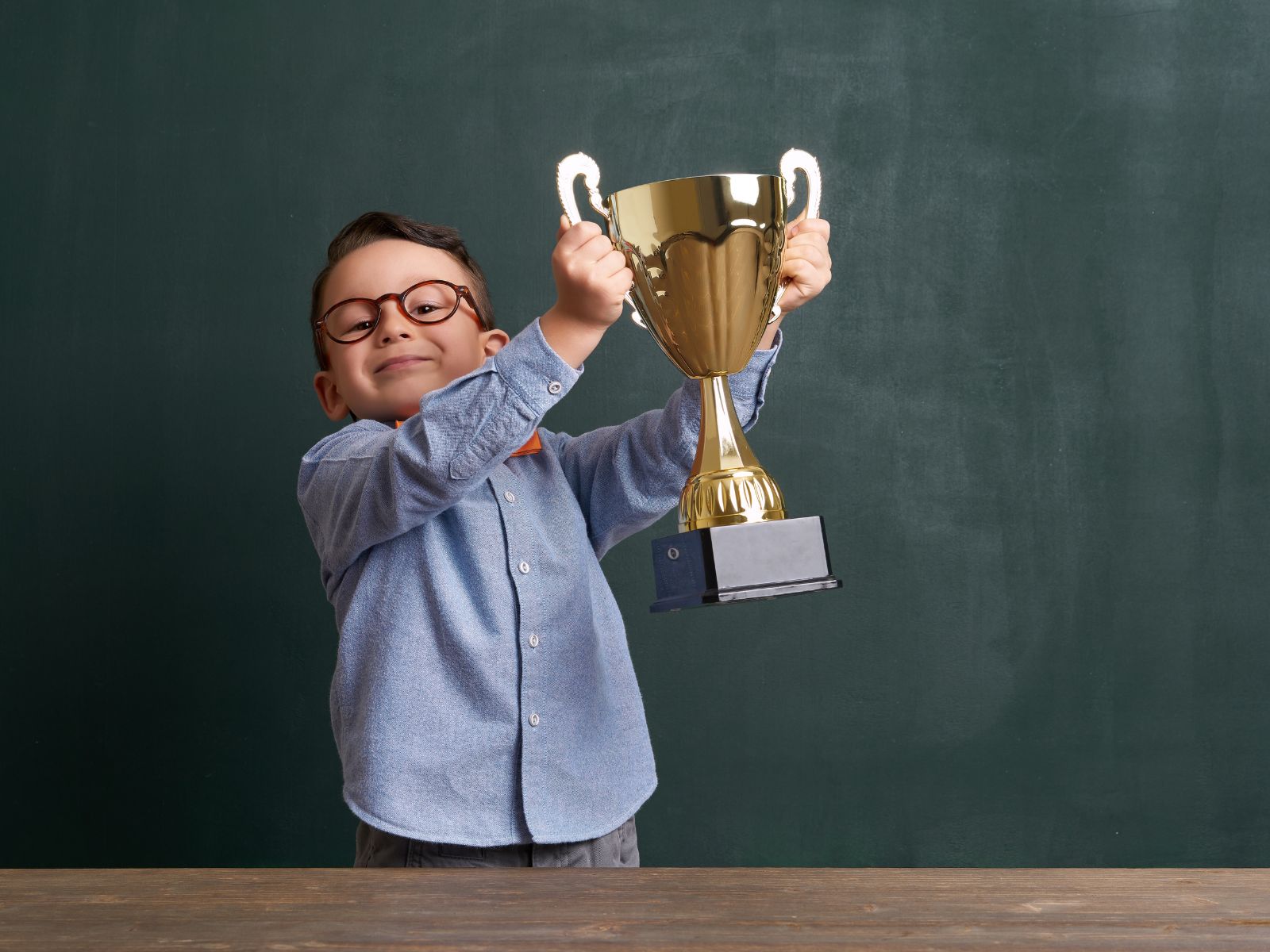 Young boy holding gold trophy in classroom, celebrating scholastic achievement with custom award