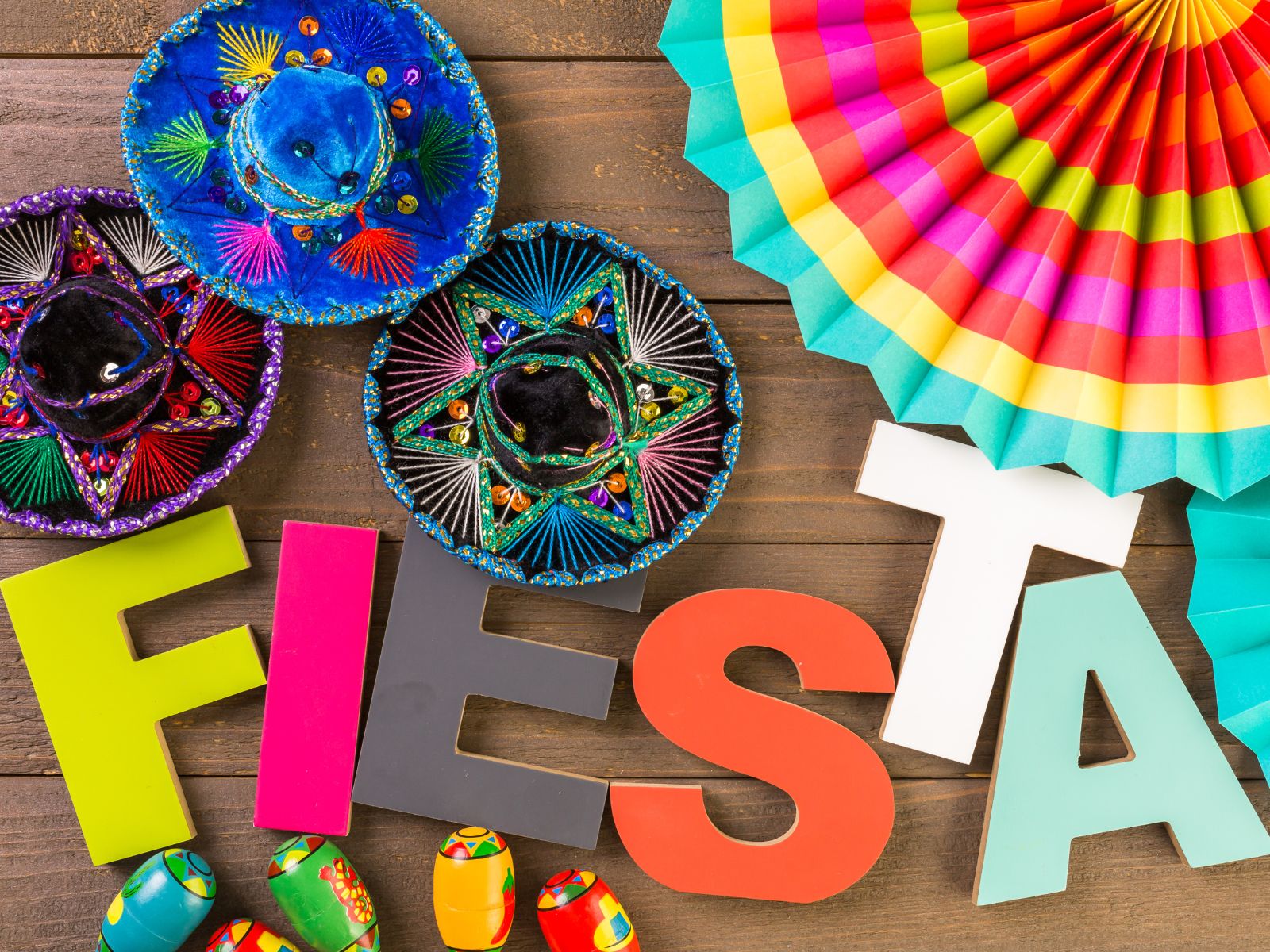 Colorful fiesta decorations with mini sombreros, maracas, paper fan, and 'FIESTA' letters on wood