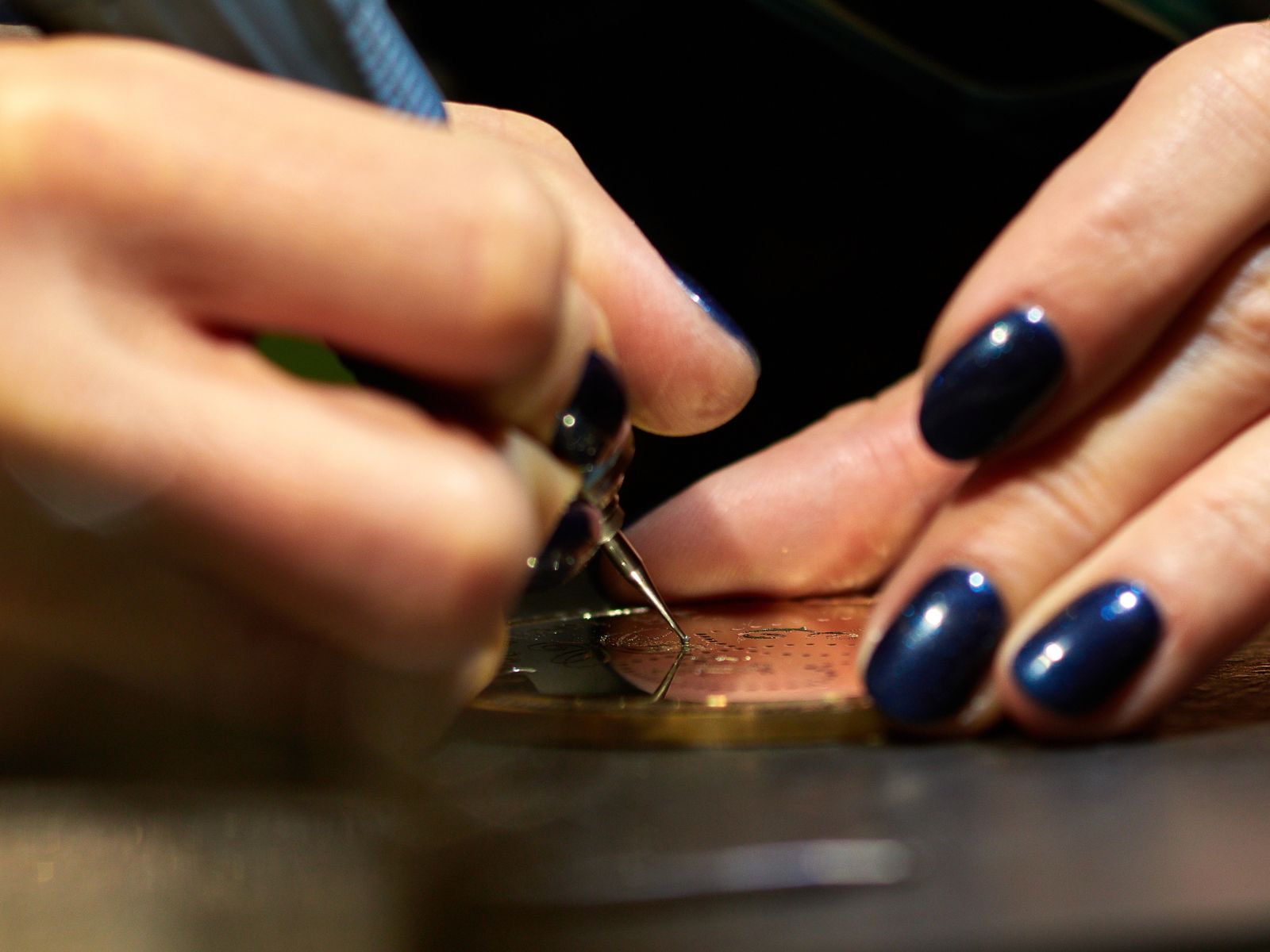 Hand engraving a custom trophy plaque with precision tool, showcasing detailed craftsmanship for awards.