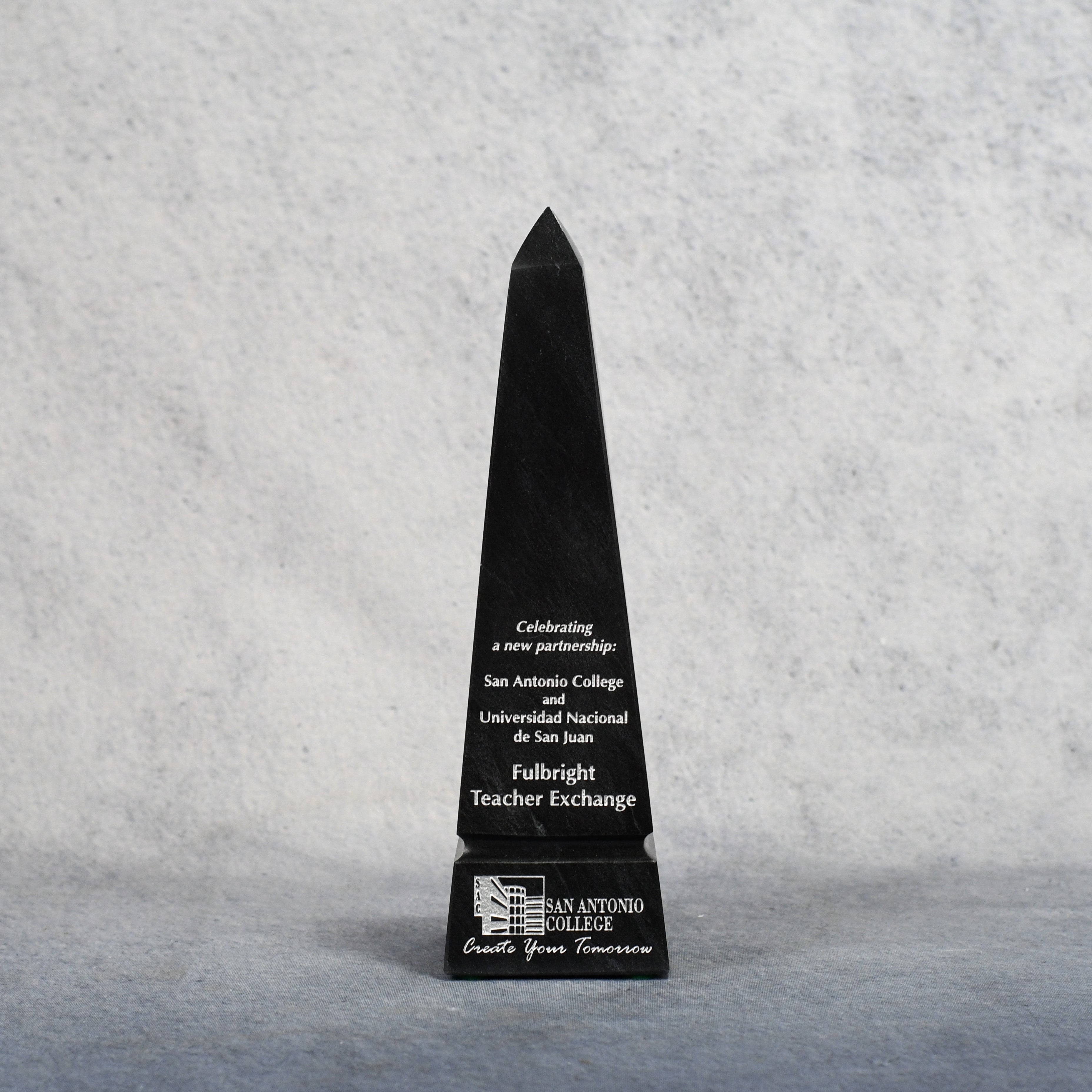 Black obelisk-shaped Monarch Trophy award with engraved text on a gray background.